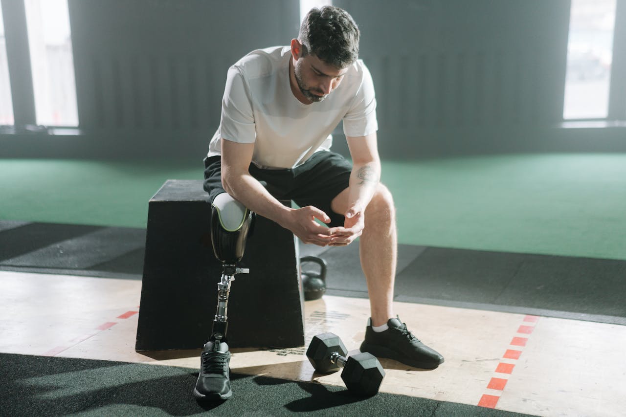Inspirational portrait of a male athlete with a prosthetic leg sitting in a gym, embracing the challenge of fitness.