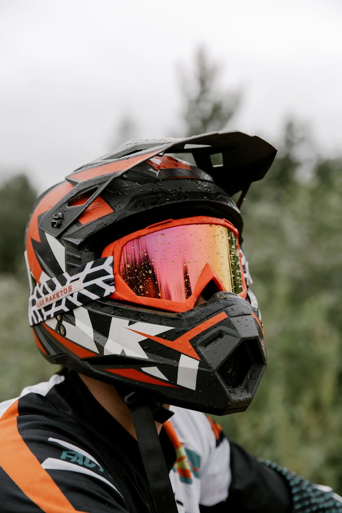 A biker wearing a colorful helmet with visor, set against a natural outdoor background.