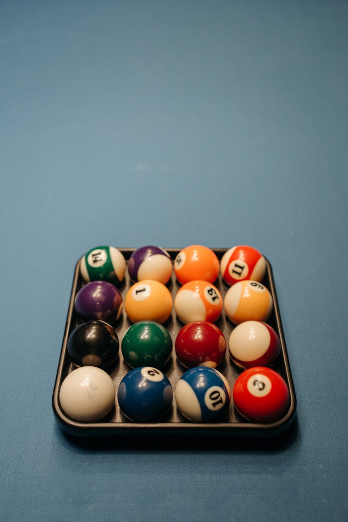 Vividly colored billiard balls neatly arranged on a blue felt pool table ready for play.